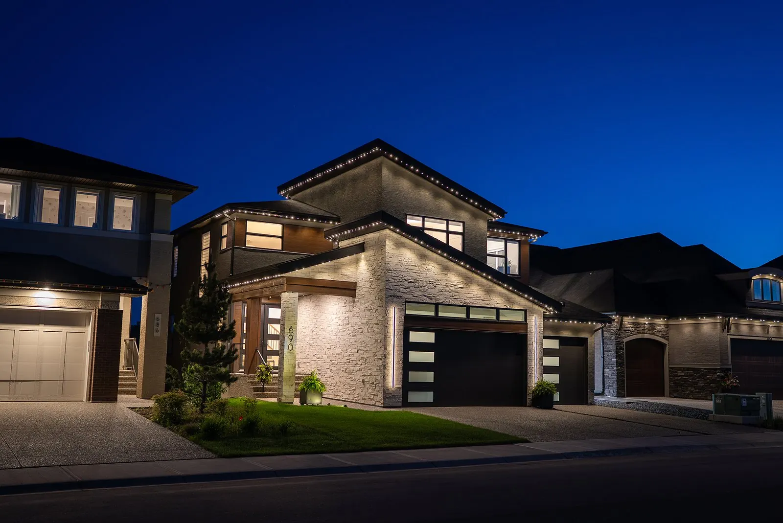 Modern home at dusk lit with warm architectural lighting