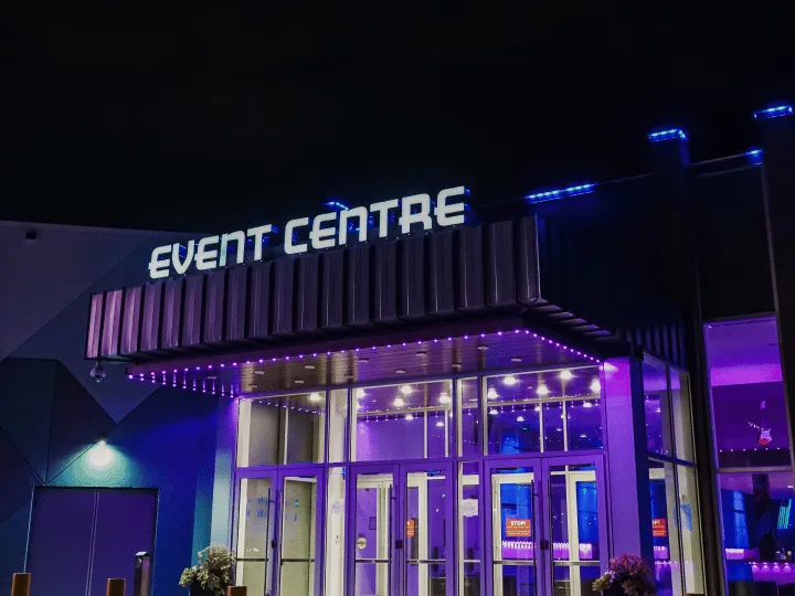 Event venue entrance at night with blue and purple lights along a flat facade