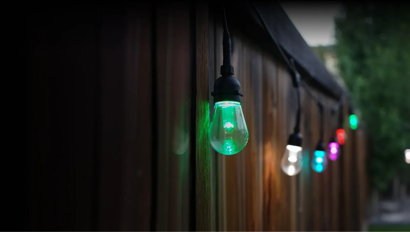 Smart patio string lights glowing in several colors along a fence