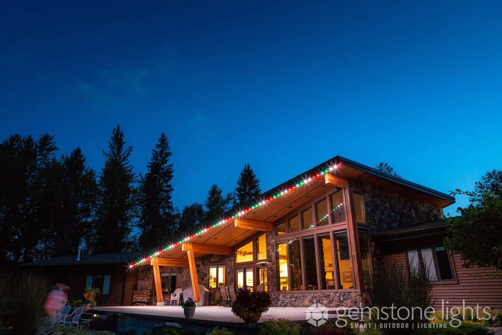 Lodge-style home with a wide porch and timber gables lit in bright orange for Halloween