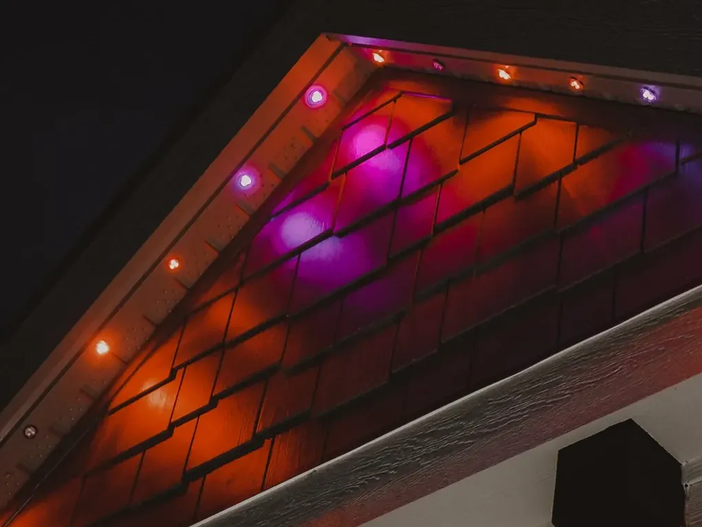 Close view of a soffit glowing orange and magenta from lights set into the roof edge