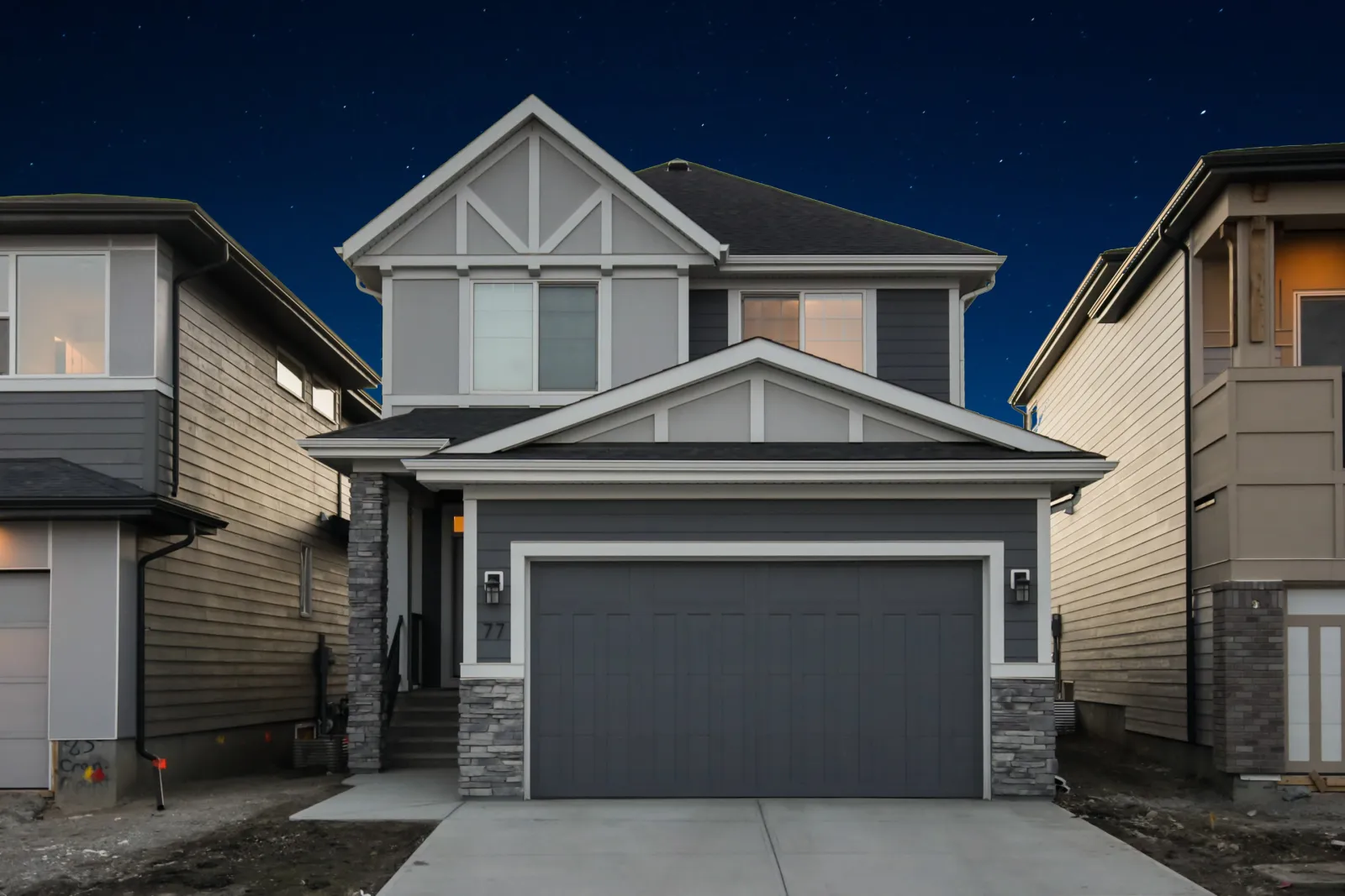 Two-story house with a gray garage door at dusk, roofline lights switched off